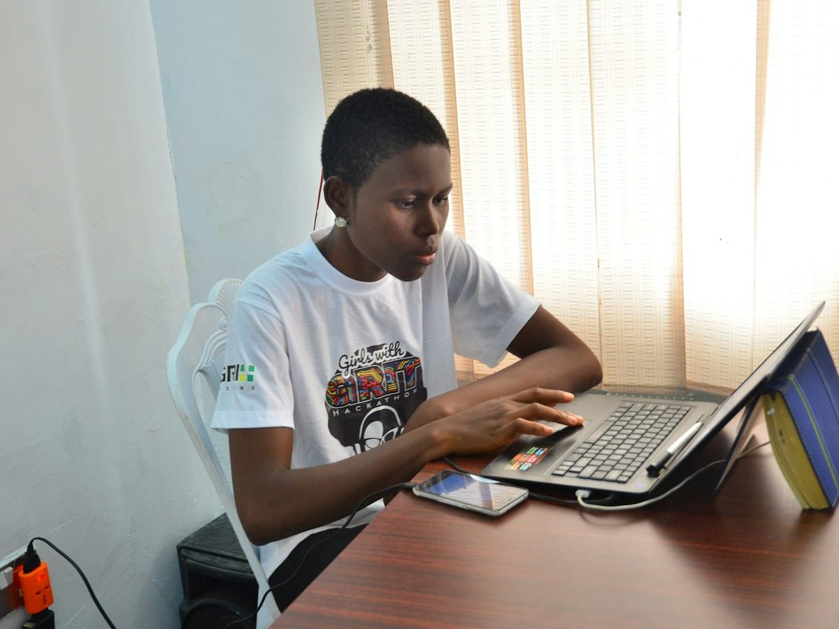 A student studying on a laptop at a desk by a window